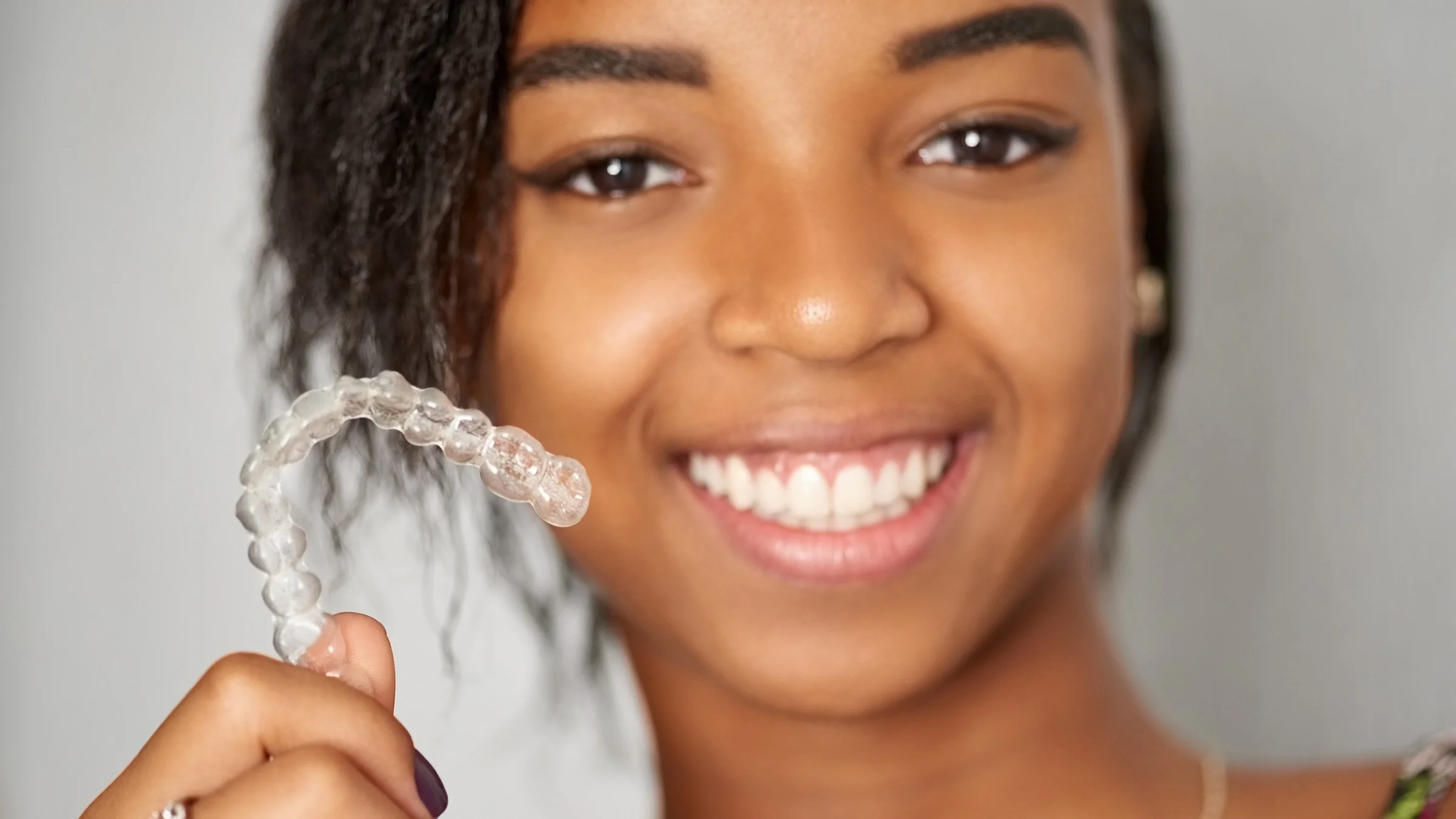 Cropped portrait of a young girl holding up her Invisalign braces.