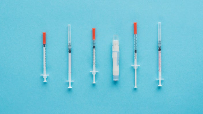 Flat lay image of different types of insulin injections on a light blue background.