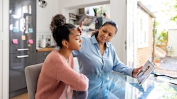 During a telehealth call, a mother gauges her daughter’s temperature by touching her hand to her daughter’s forehead
andresr/E+ via Getty Images 