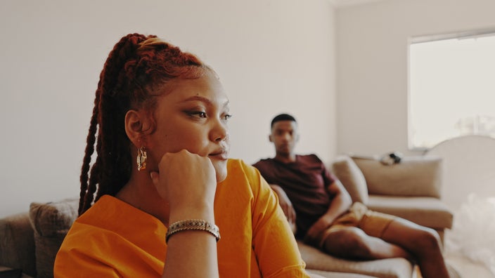 Couple having a difficult time at home. The man is in the background blurry.