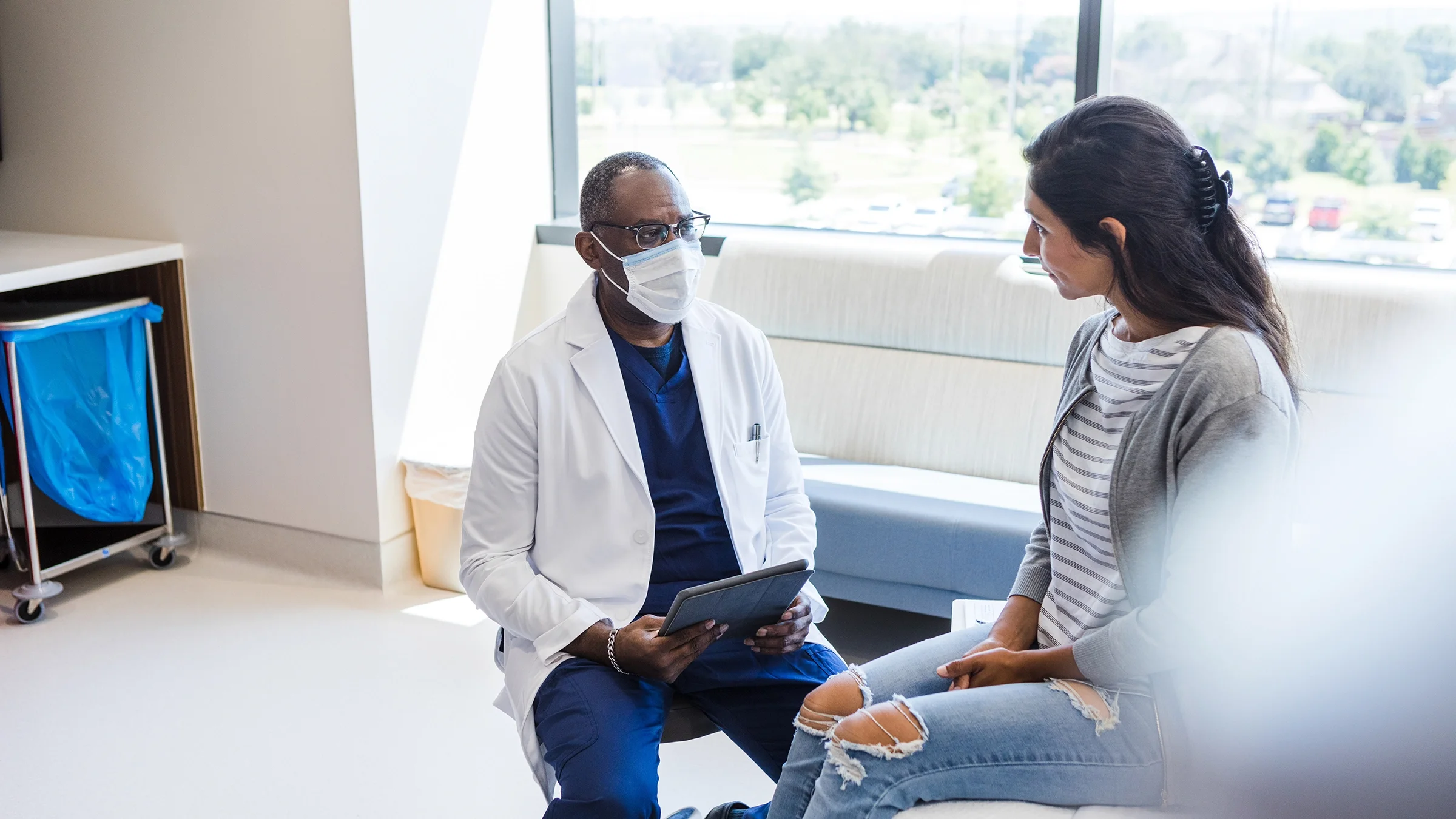 A healthcare provider is talking with a patient with his digital tablet to review options.