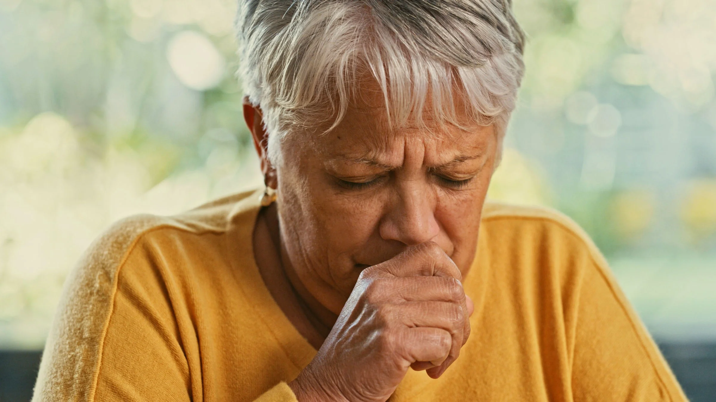 An older woman is coughing.