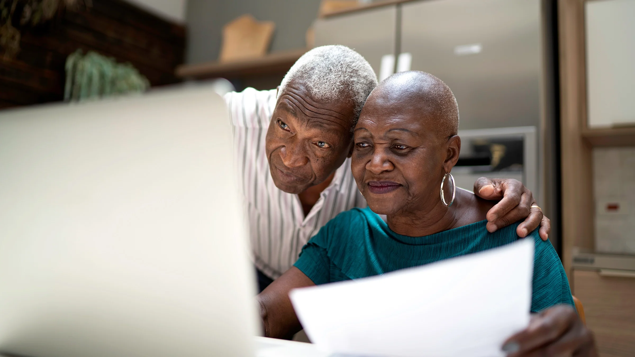 A senior couple does finances on a computer.