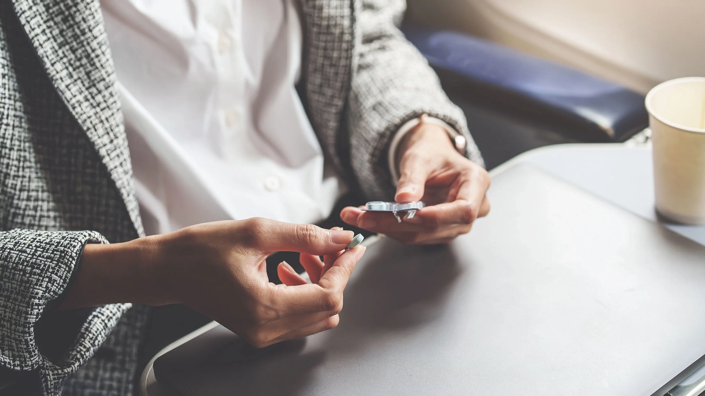 A woman takes medication on an airplane.