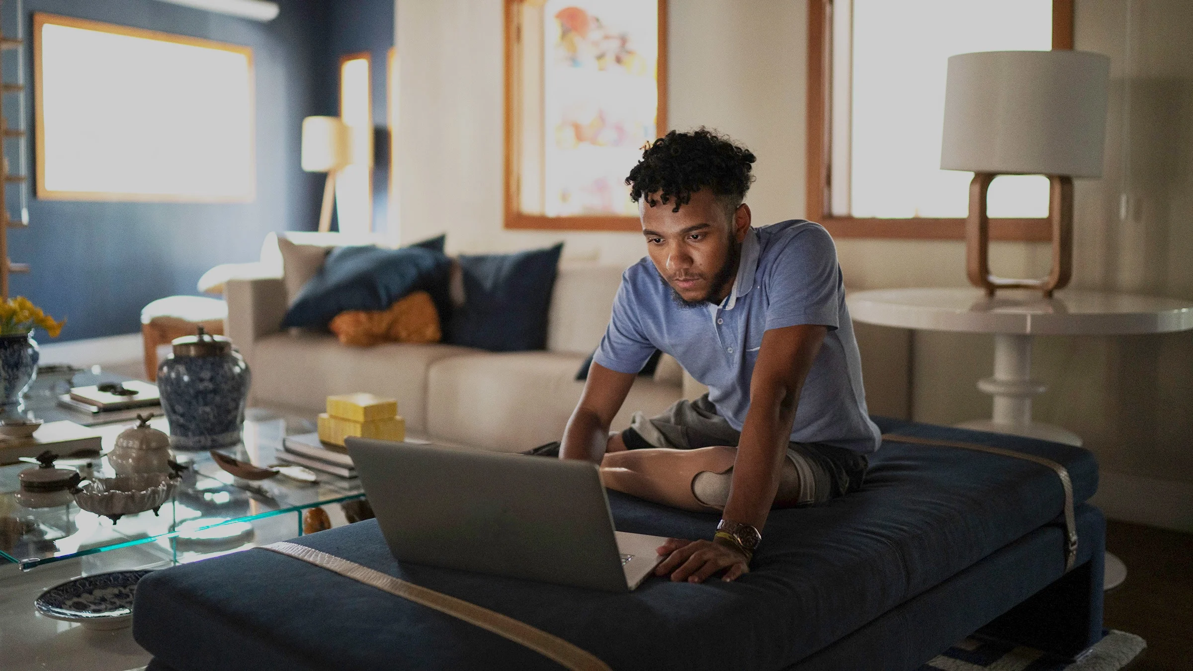 Man on his laptop in his living room researching something. He is looking intently at the screen.