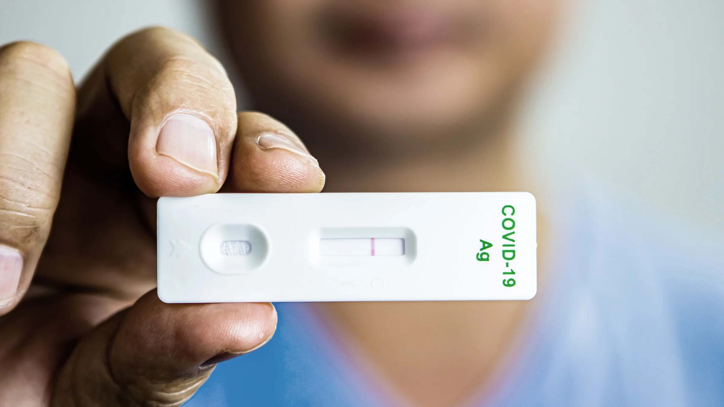 Close-up of a healthcare profession holding up COVID-19 test results to camera.
