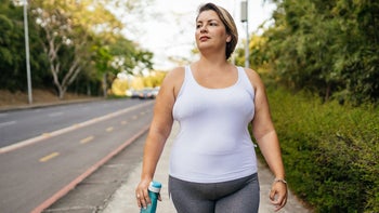 Movement-exercise: woman walking outdoors with a water bottle 1343458118