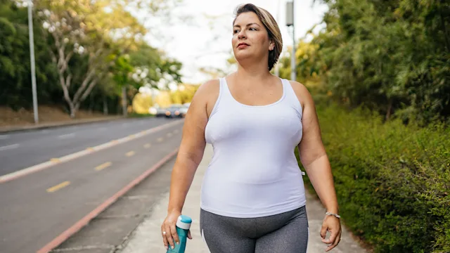 Movement-exercise: woman walking outdoors with a water bottle 1343458118