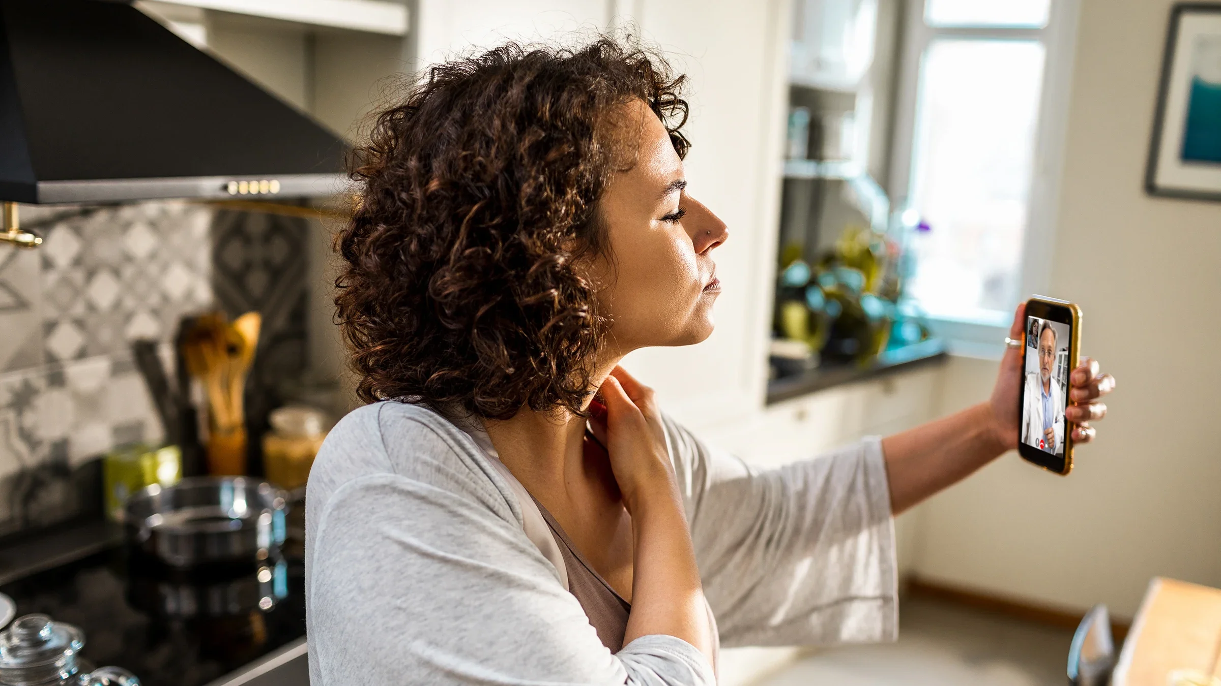 A woman talks with her healthcare professional about her sore throat, which can be caused by postnasal drip. 
Geber86/iStock via Getty Images Plus