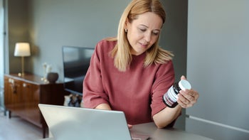 menopause: woman researching supplement on laptop 2206912467