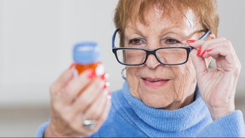 Health: anticoagulants: senior woman reviewing medication bottle-540492486