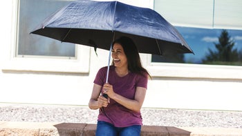 Dermatology: woman sitting under a umbrella for sun protection 1218851651