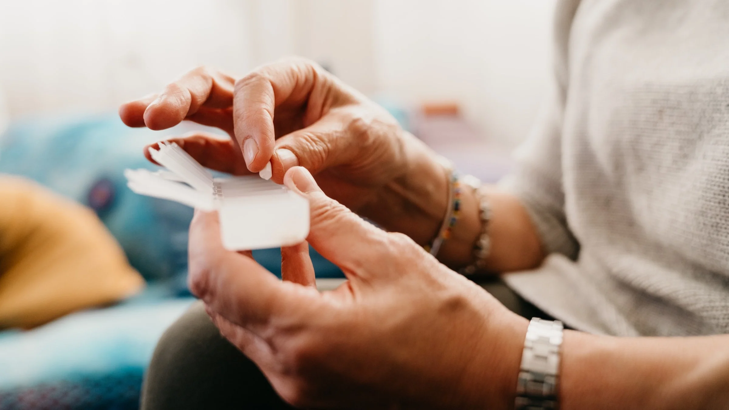 Close-up of an older woman taking and organizing her pills in a clear daily medicine organizer.