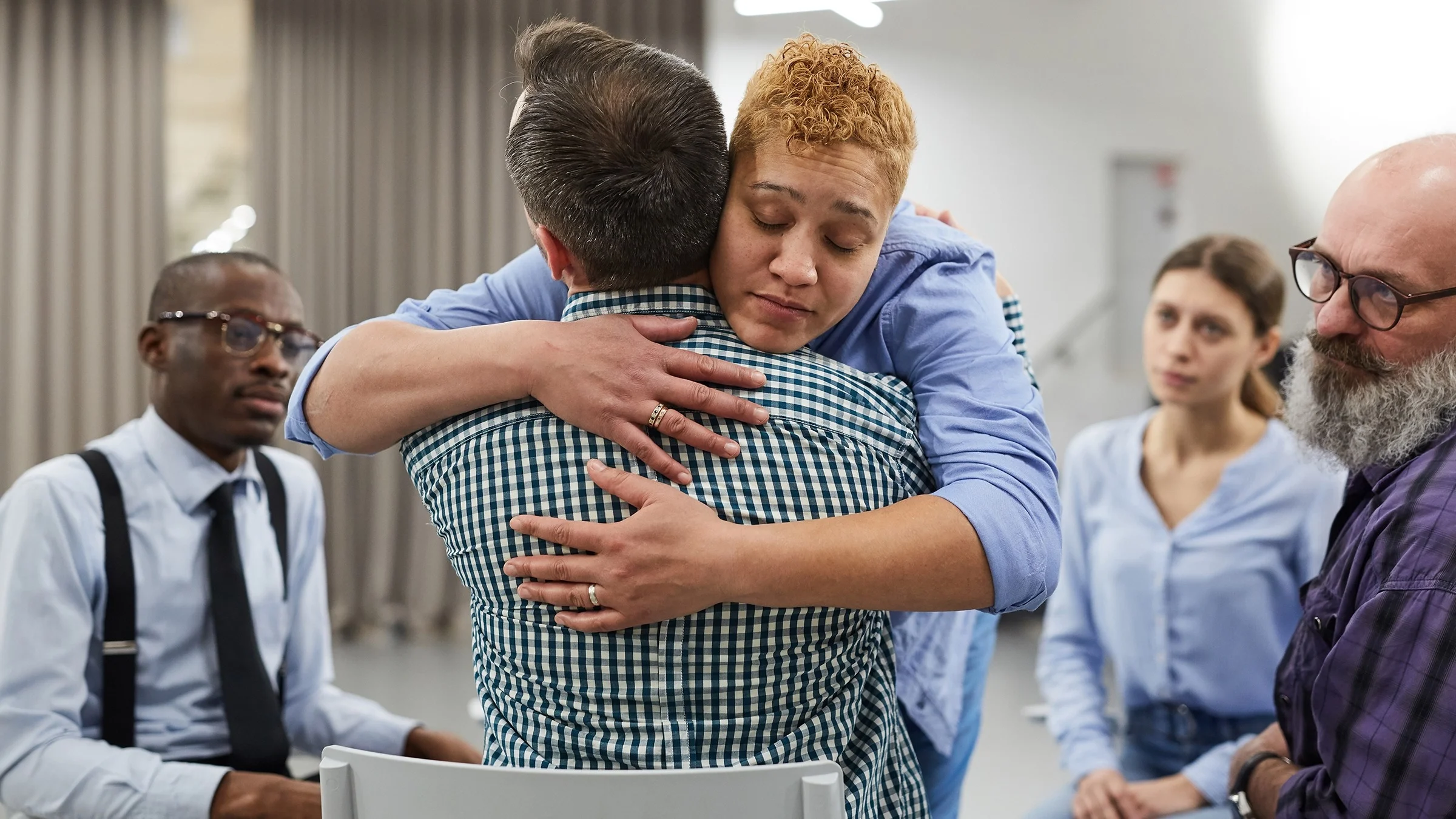 Compassionate support group meeting. Two people are hugging during a session.