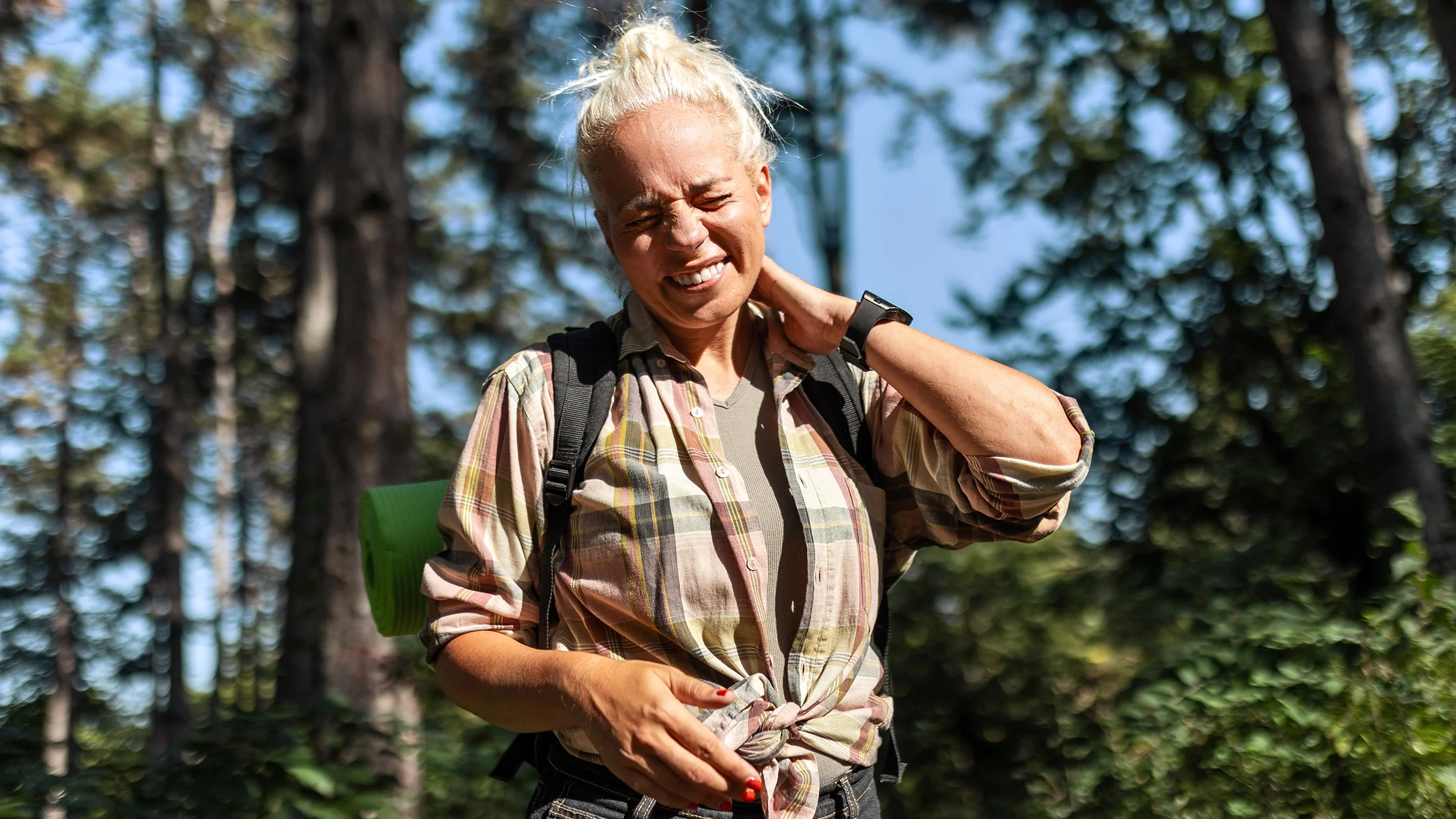 Woman outdoors itching from a bug bite.