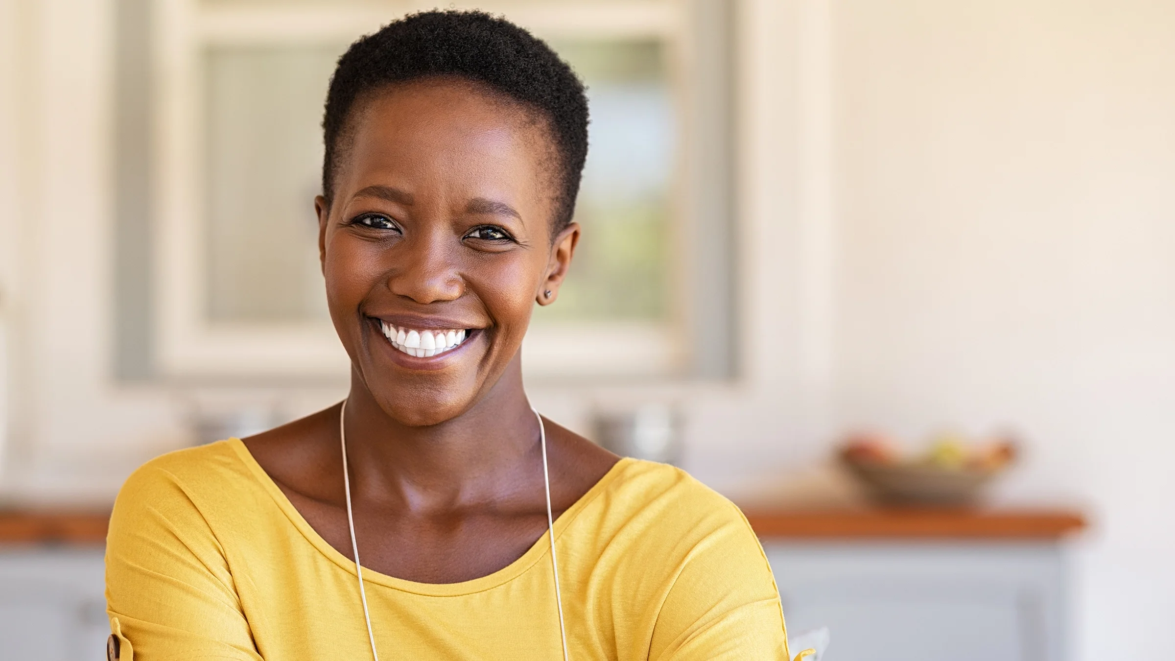 Portrait of a young woman with short hair and yellow shirt.