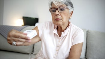 Abilify: senior woman reading rx box 1342241277