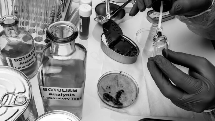 Close-up on a lab technician’s hands doing Botulism tests on canned food.