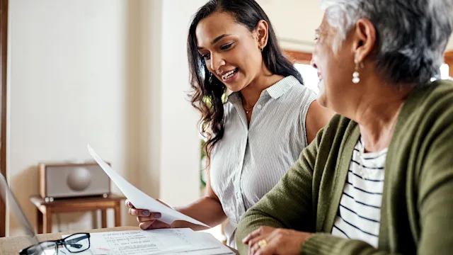 Digital-Health: woman helping elder with finances 1181408144