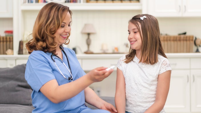 A doctor explaining an injection pen to a young girl.