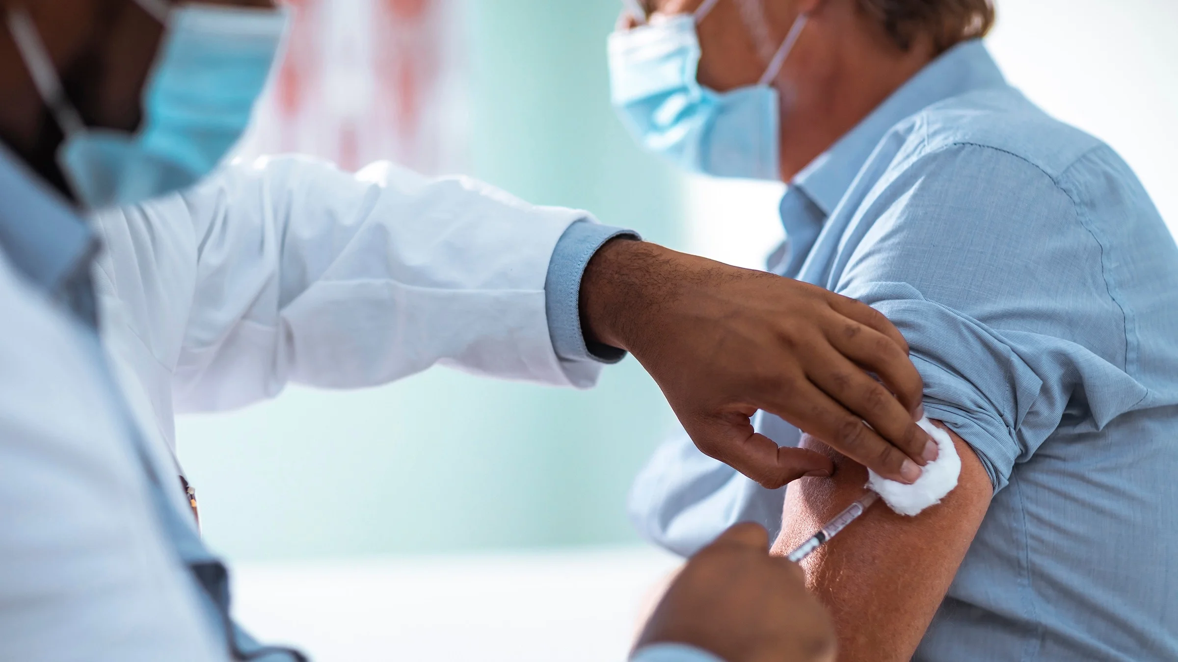 Cropped shot of a man getting a COVID-19 vaccine shot from a doctor.
