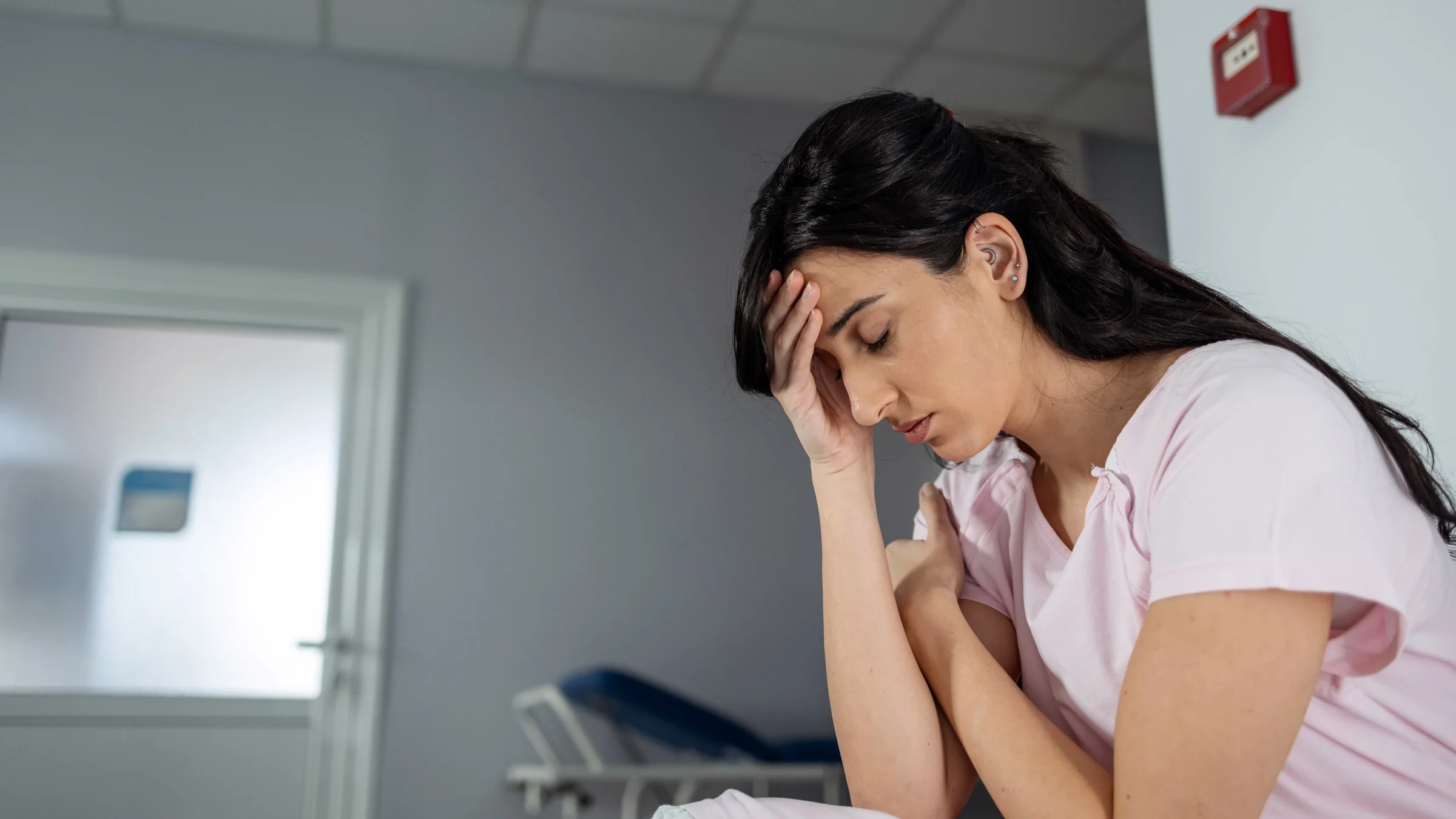 A person sitting in a hospital waiting room with a headache.