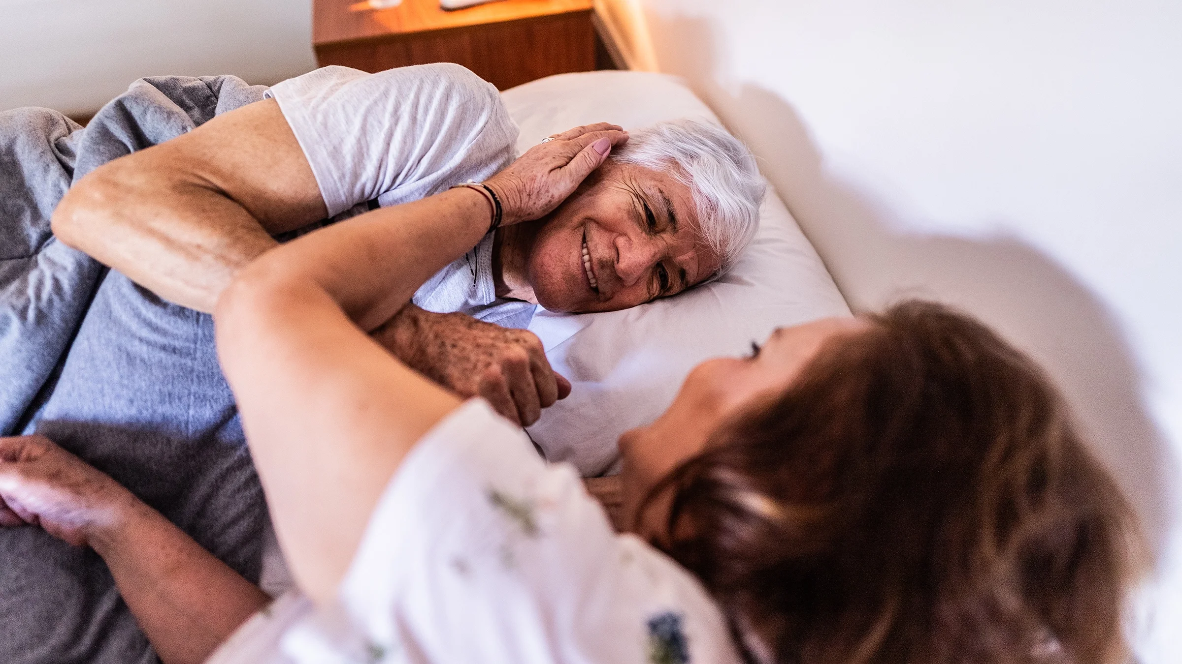 A couple lie in bed.