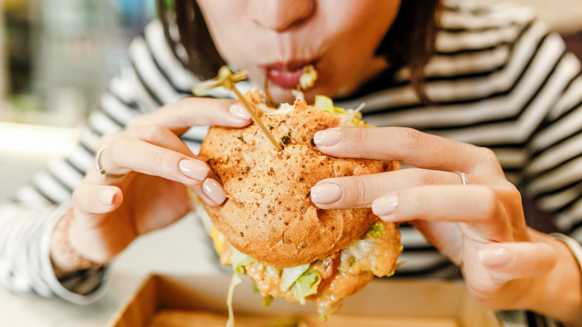 Close-up of a woman eating a fried chicken sandwich.