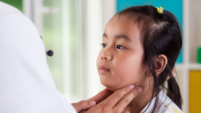 Pediatrician examining a young girl's lymph nodes. The little girl has black hair tied up in a ponytail.
