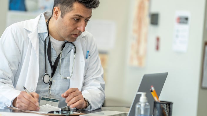A telehealth doctor filling out a prescription pad.