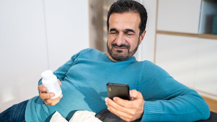 A man searches for pill instructions on a smartphone.