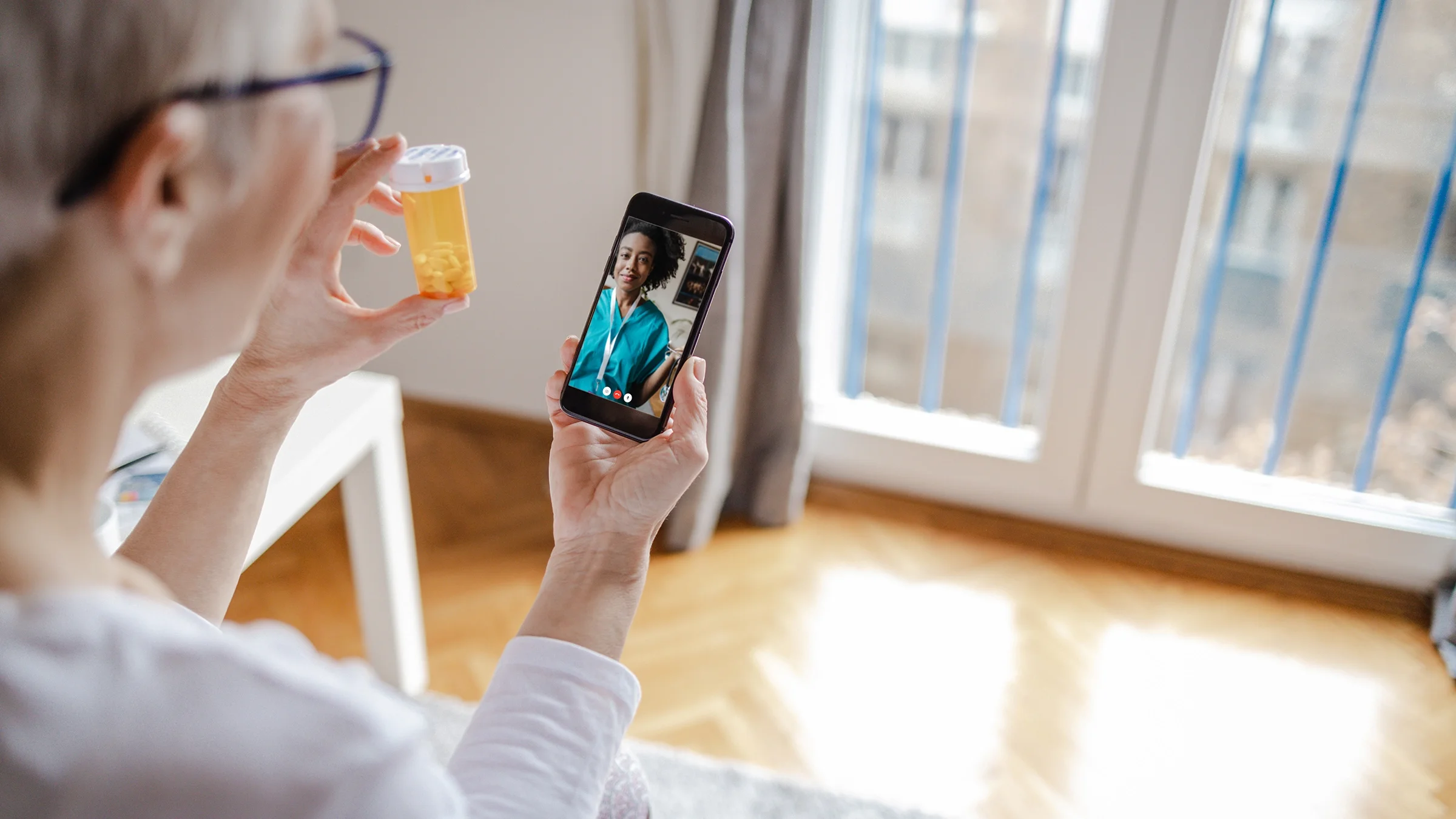 Woman holds a bottle of medicine in her hand during a telemedicine appointment.