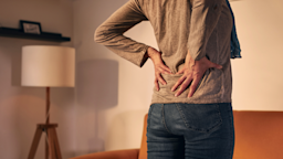 A woman clutches her lower back in pain.
m-gucci/iStock via Getty Images Plus