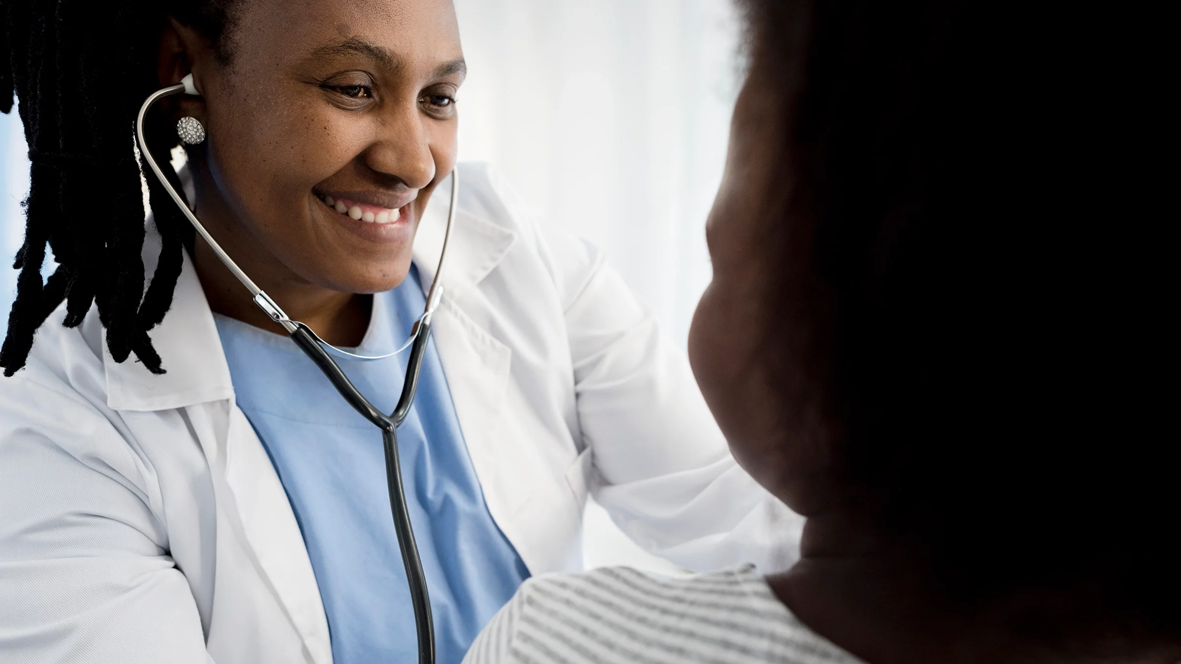 Close-up of a doctor checking a patient. The doctor has a soft smile on their face.