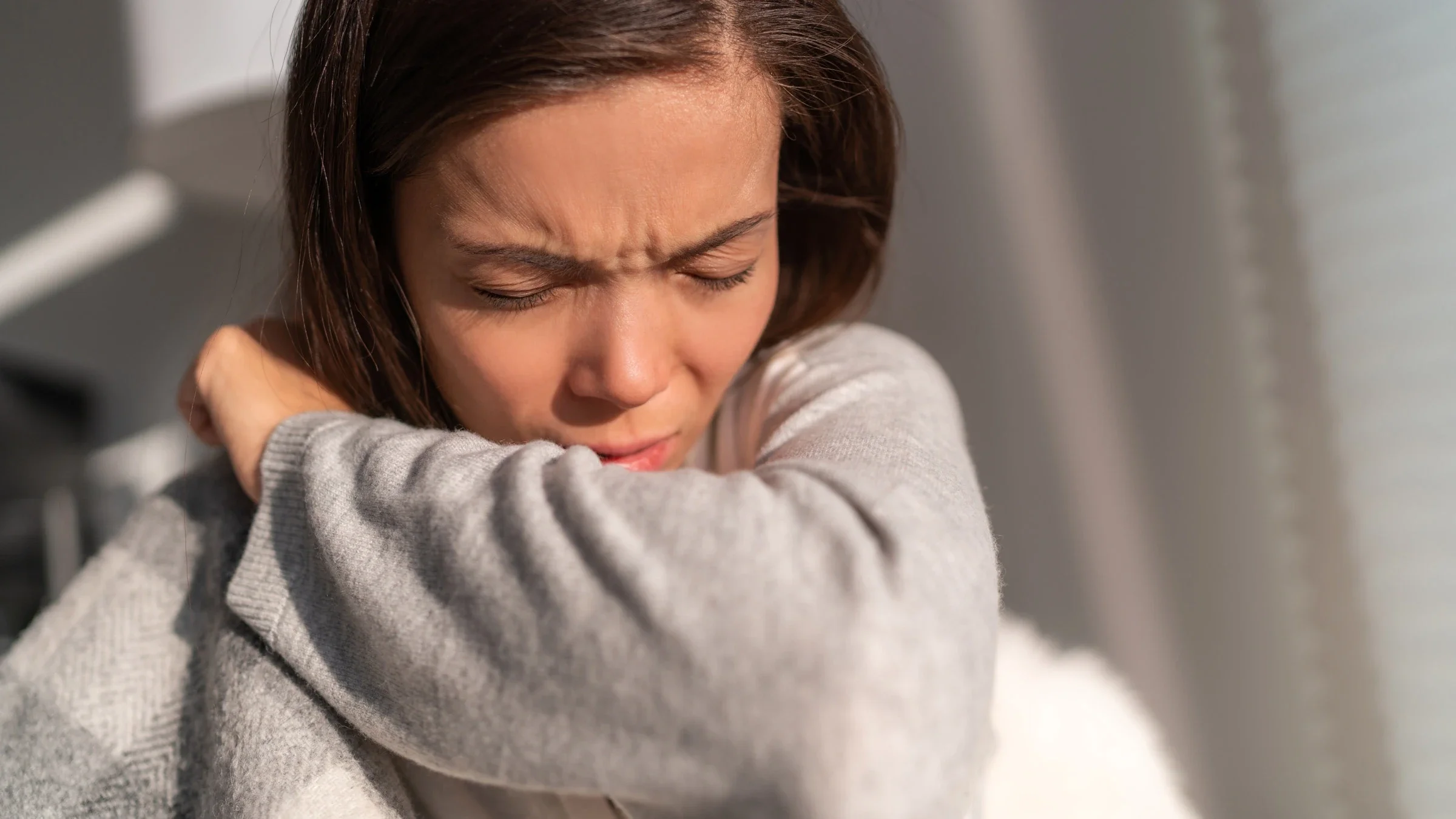 A woman coughs while at home. Respiratory syncytial virus (RSV) can cause serious illness, such as pneumonia, among older adults. 