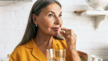 supplements-herbs: woman taking supplement with water 2217243898