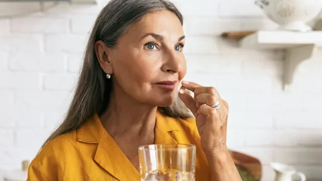 supplements-herbs: woman taking supplement with water 2217243898
