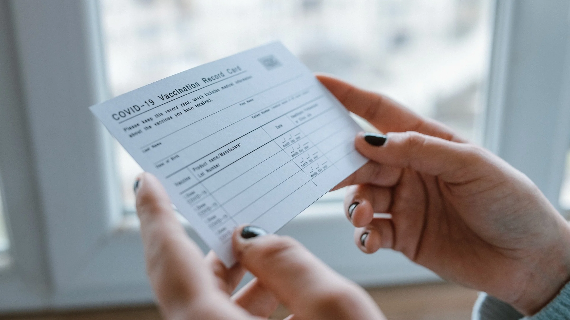 Close-up on a person holding a vaccine card in their hands.