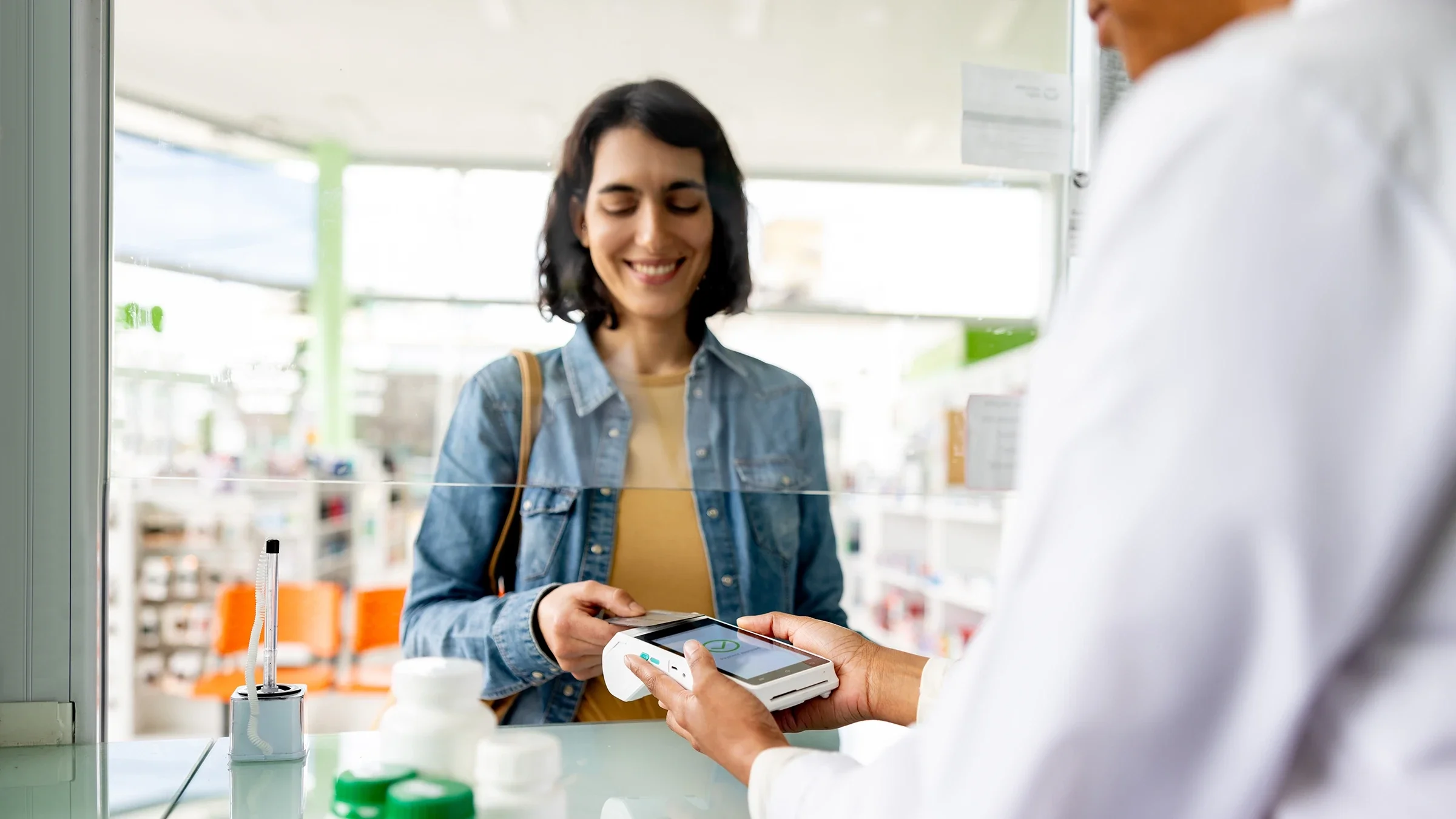 A woman pays with a card at the pharmacy.