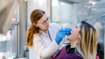 Health: dental care: dentist examining patients mouth-1387250140