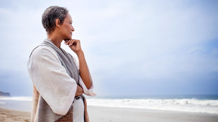 Senior woman stares at the ocean in a meditative state.