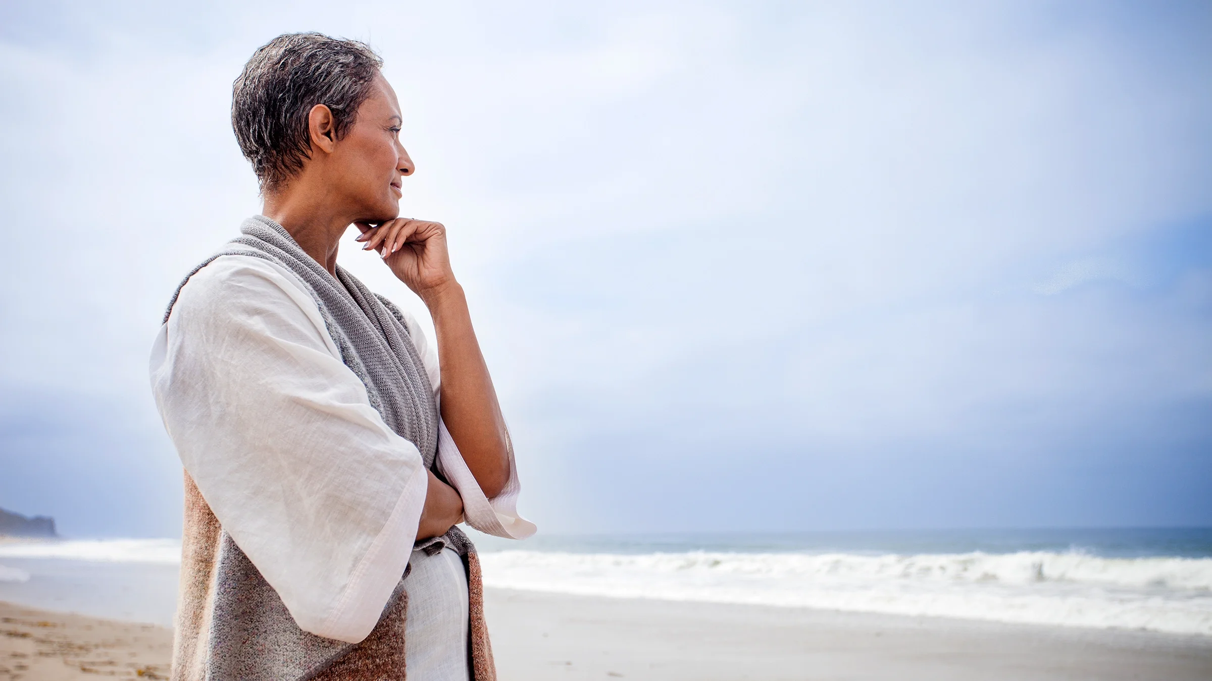 Senior woman stares at the ocean in a meditative state.
