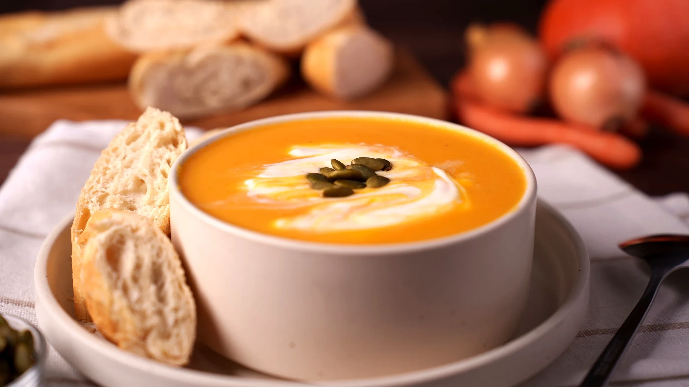 Bowl of pumpkin soup topped with cream and seeds.