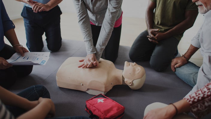 Close-up of a CPR class in a circle watching a demonstration.