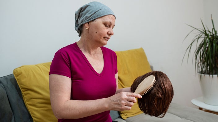 A cancer patient brushing their wig.