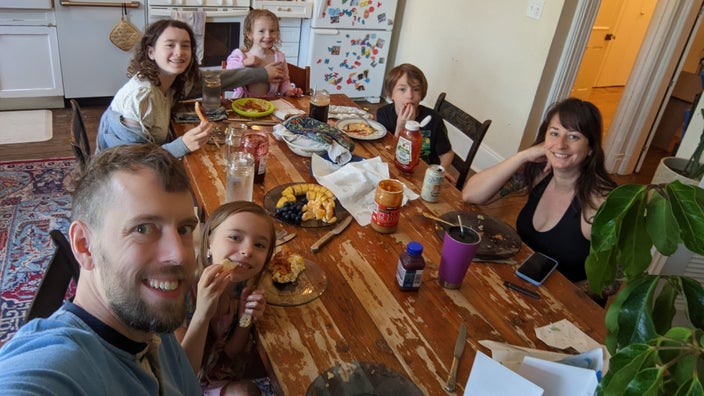 Juliet Davis is pictured sitting at the kitchen table with her husband and their four kids.