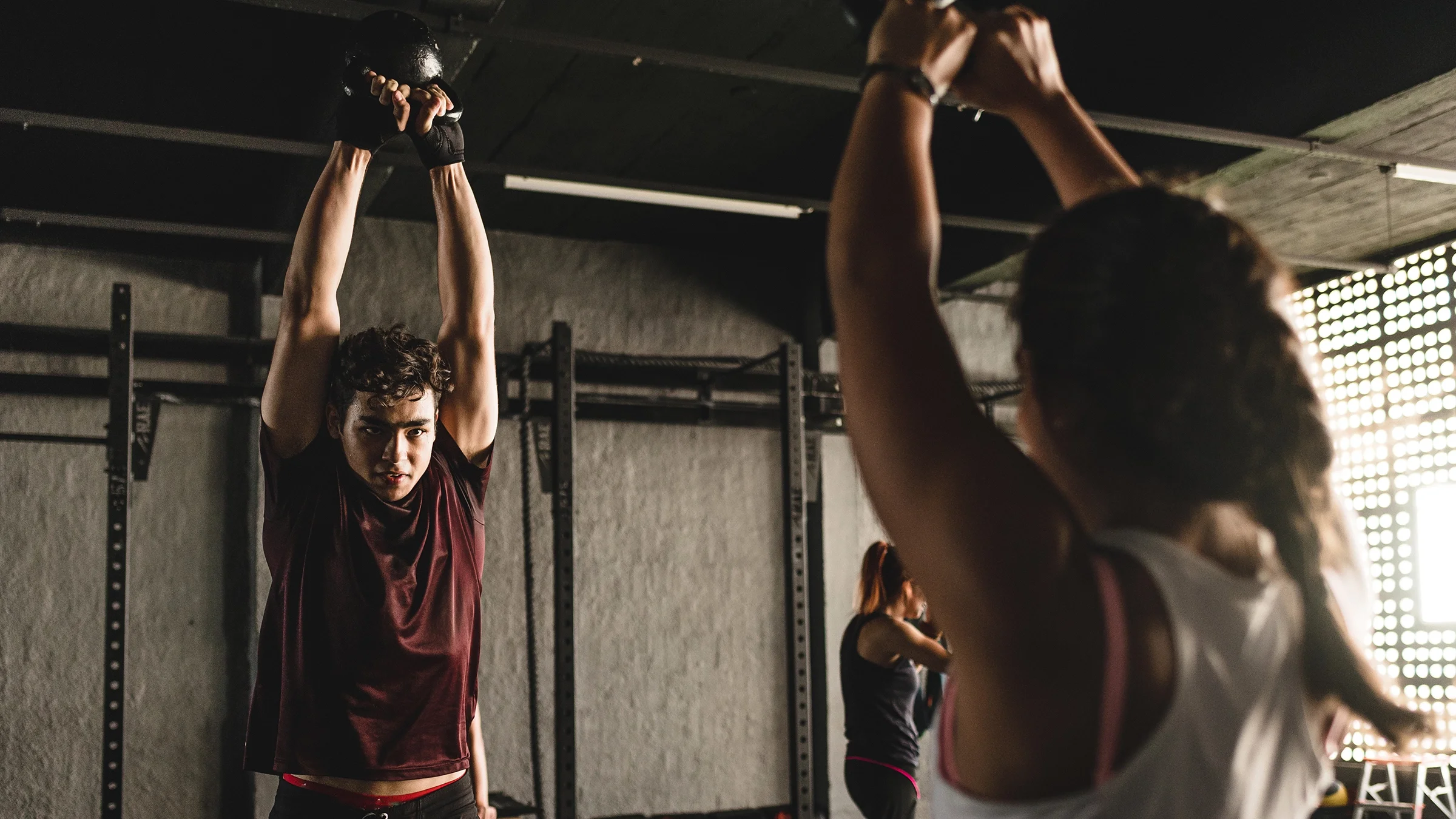 Man and woman doing kettlebell exercise at the gym.