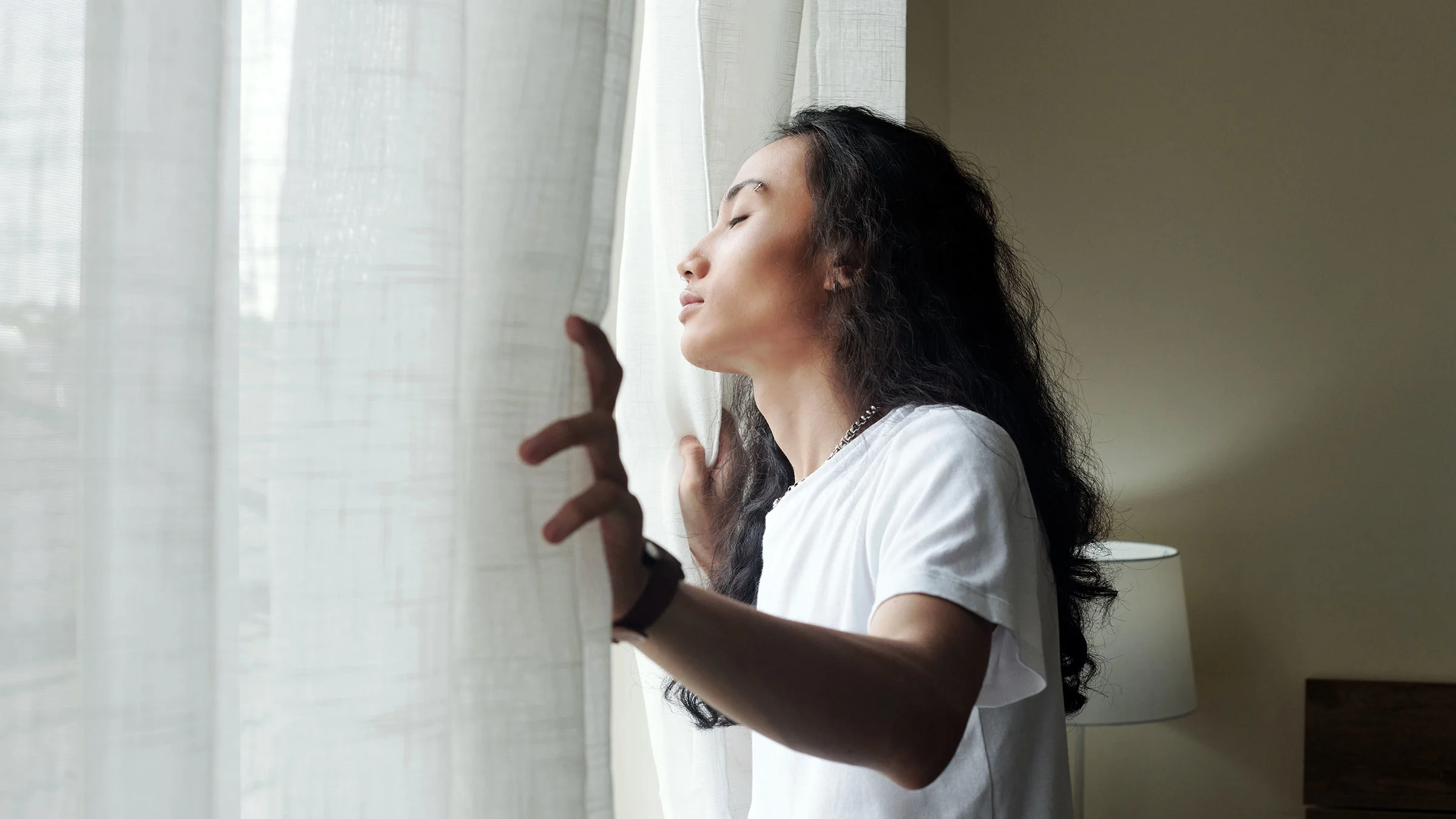 Person opening curtains and enjoying first rays of sun