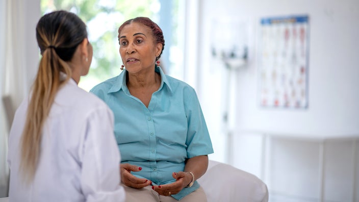 Woman sitting on an exam table and speaking with a doctor