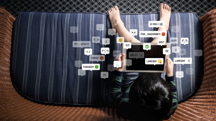 Child using tablet with illustrations of cyberbullying emoticons.